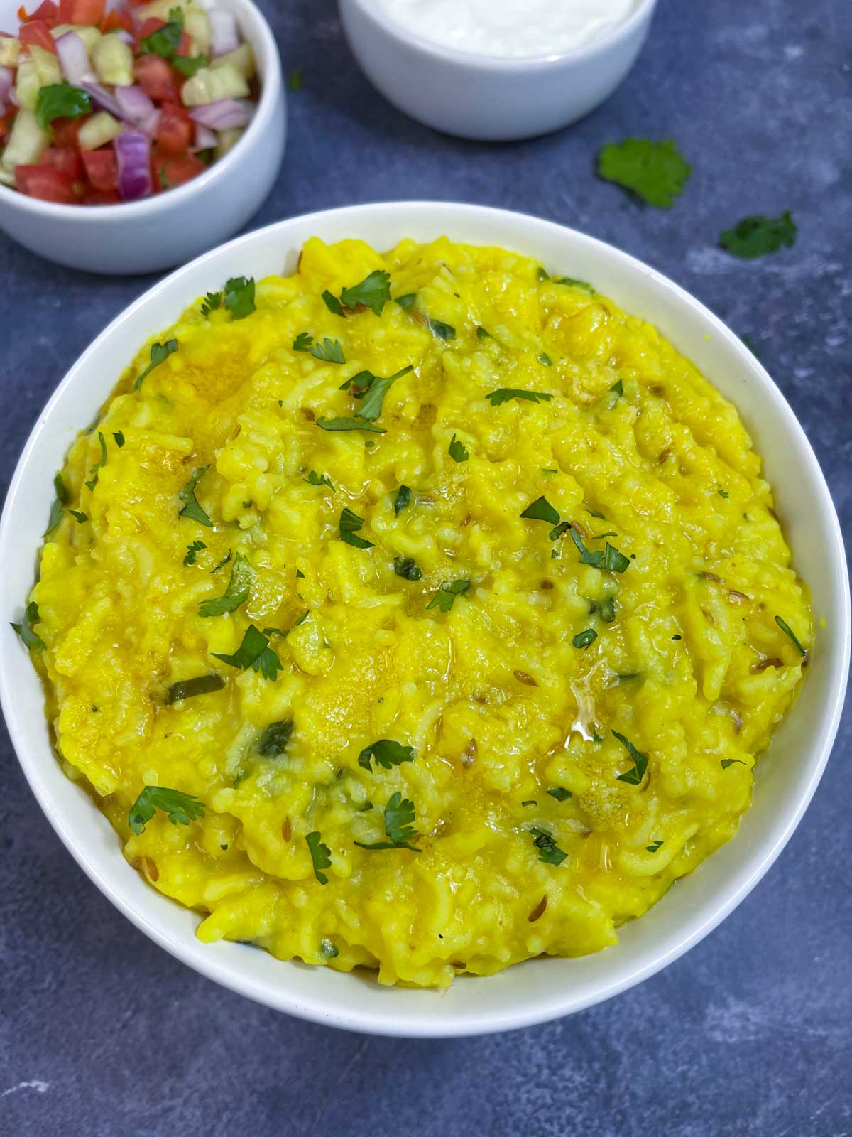 Instant pot Moong Dal Khichdi (khichri) served in a bowl garnished with cilantro with salad on the side