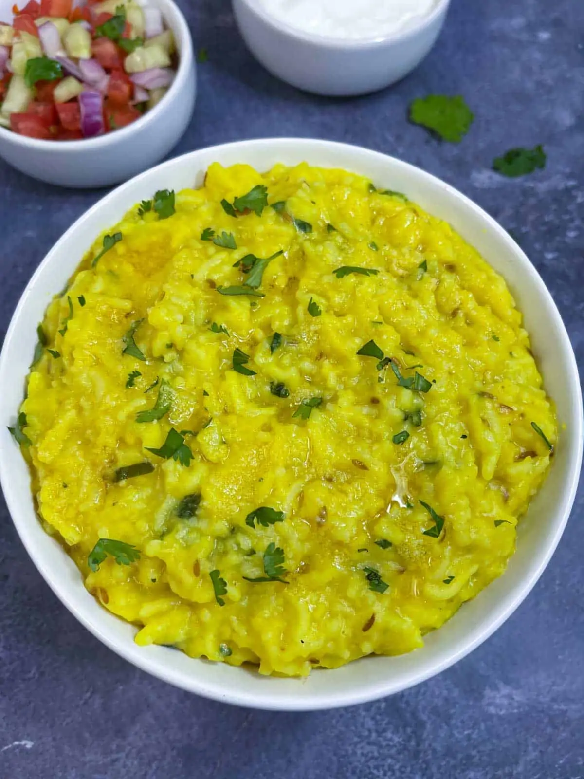 Moong Dal Khichdi served in a bowl garnished with cilantro with salad on the side