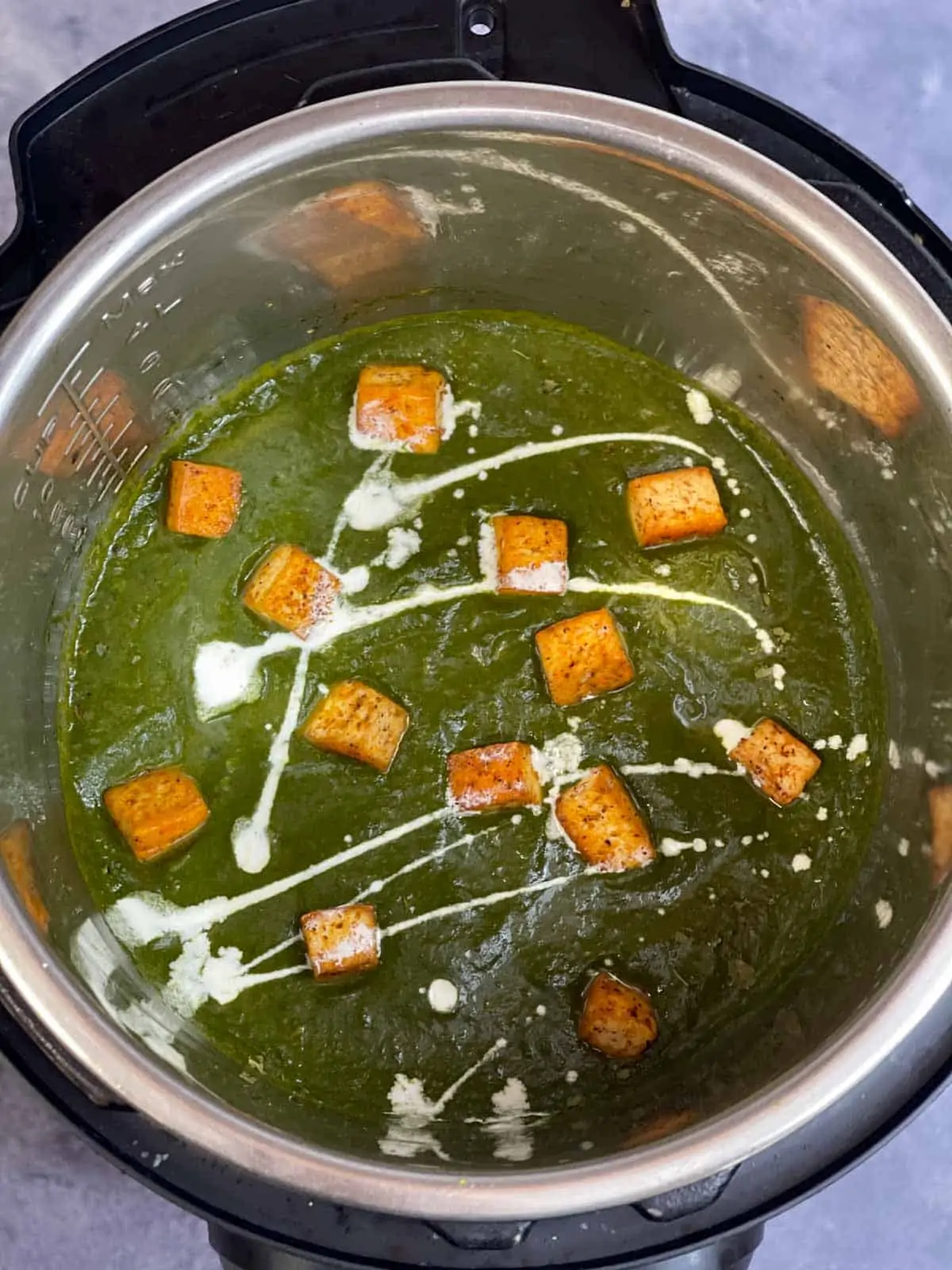 Palak tofu curry in instant pot garnished with fried tofu and cream