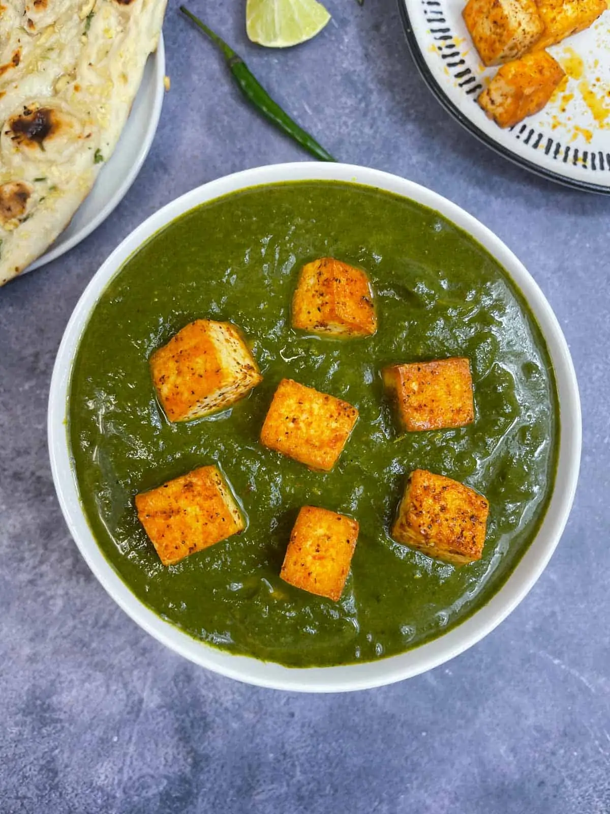 palak tofu served in a bowl topped with fried tofu with side of naan 