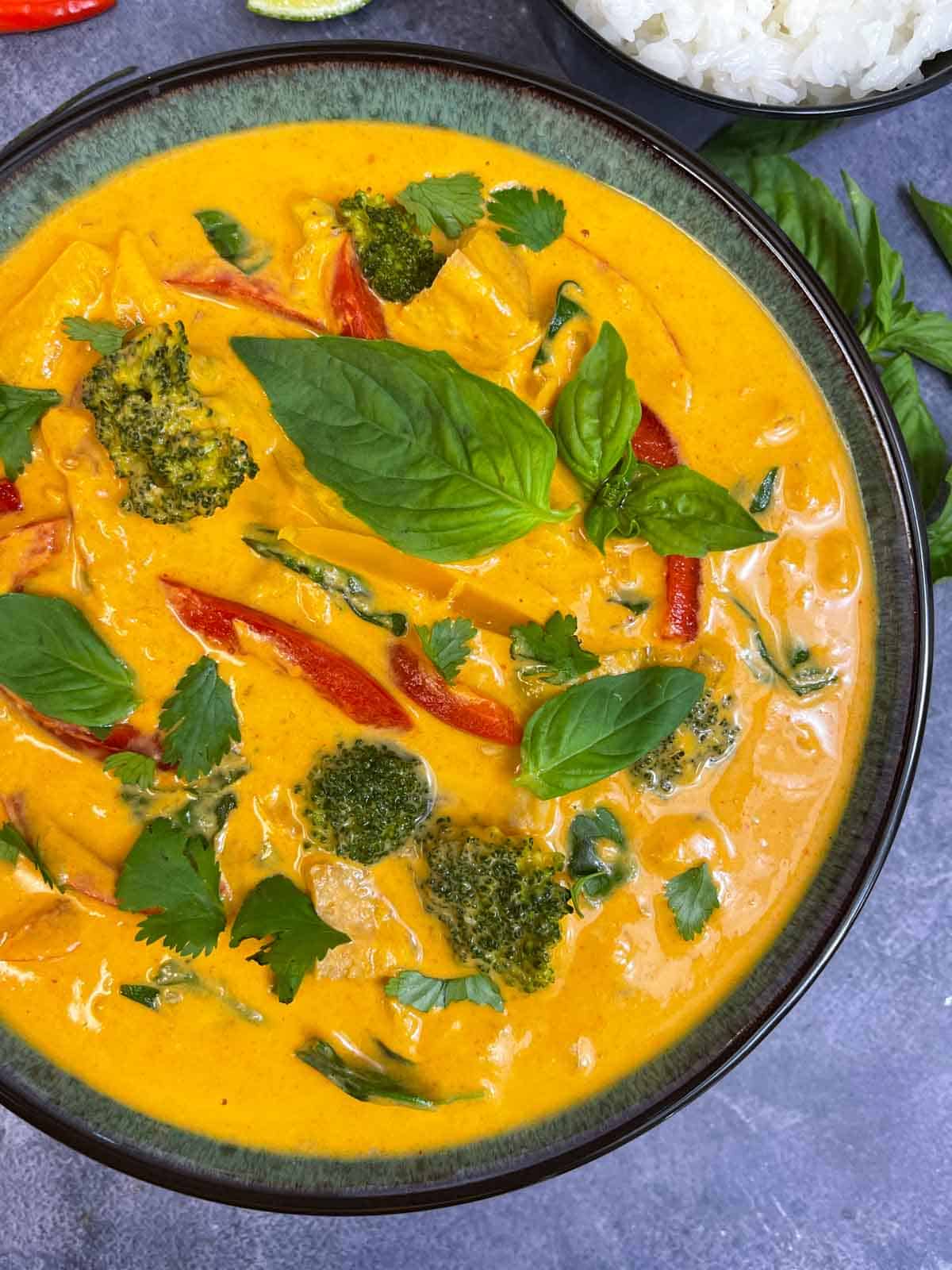 thai panang curry served in a bowl garnished with thai basil leaves 