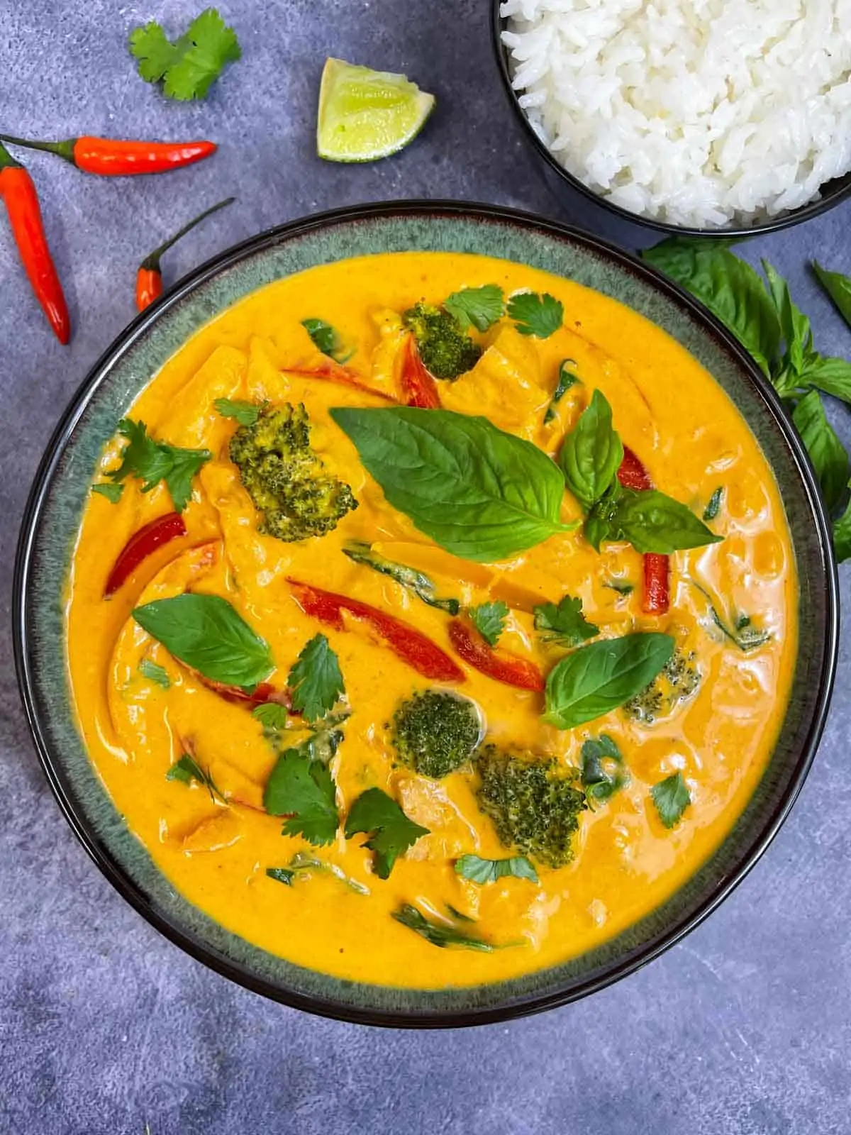 thai panang curry served in a bowl garnished with thai basil with side of jasmine rice