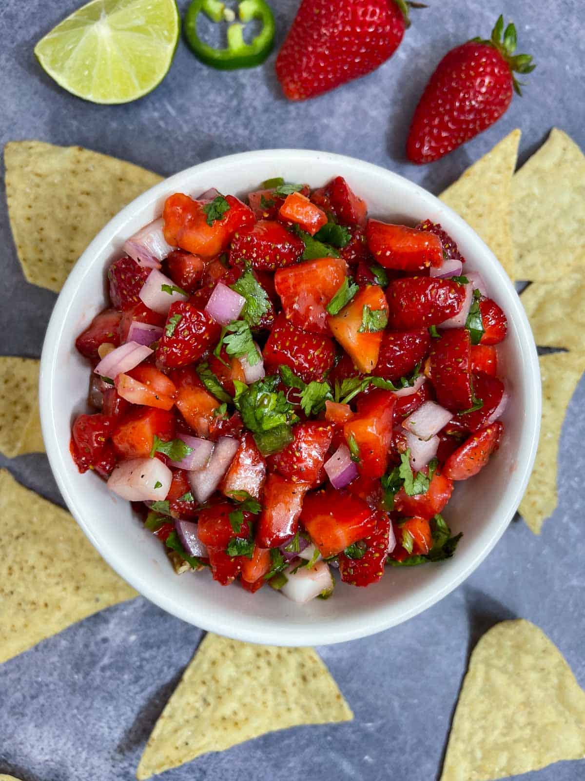 strawberry salsa served in a bowl with side of tortilla chips