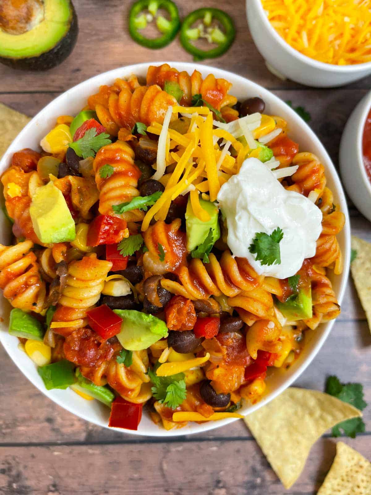 vegetarian taco pasta served on a bowl garnished with cheese, avocado ,cilantro and sour cream