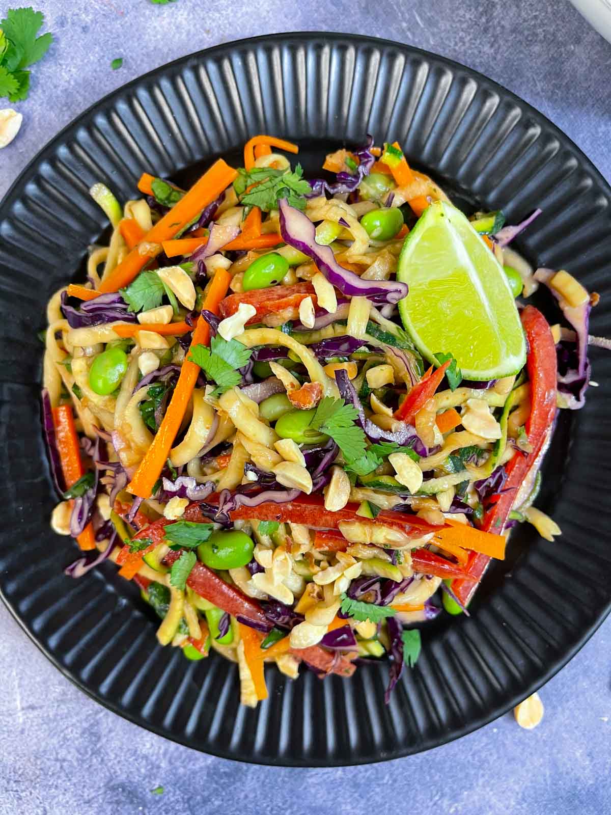 thai peanut zucchini noodles served on a plate with lime wedge on top