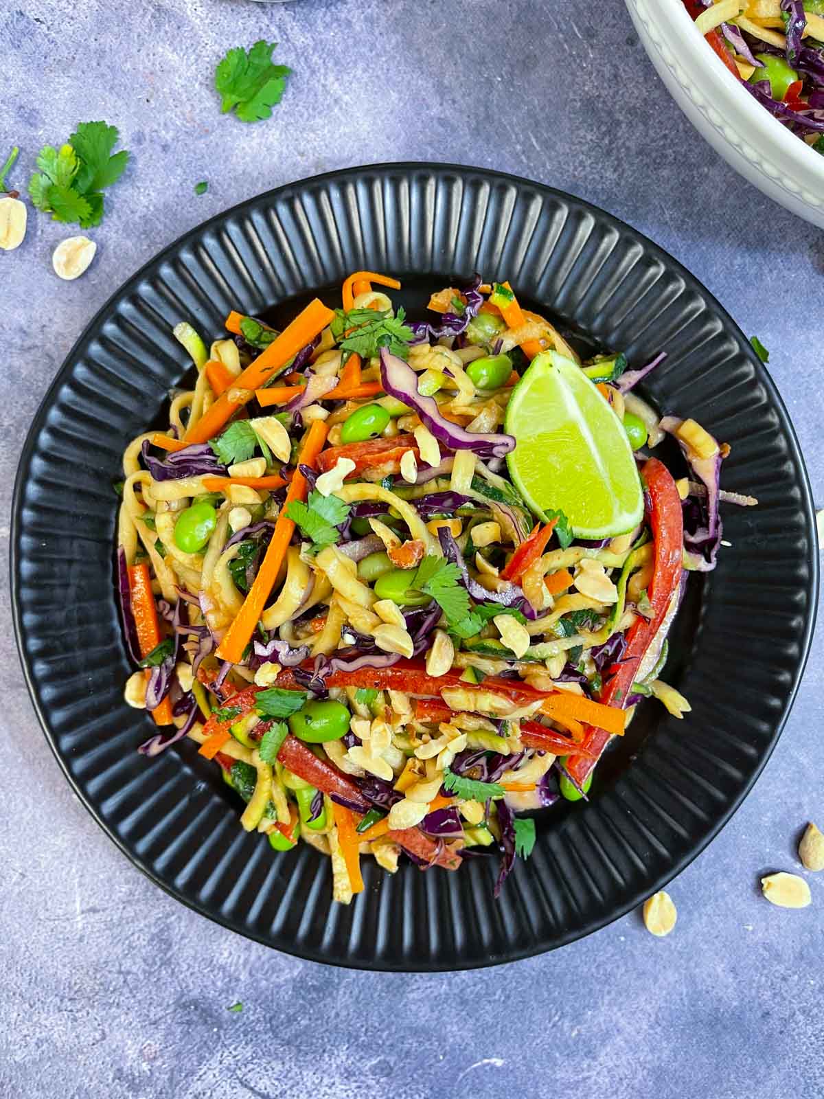 Zucchini Noodles Salad with Creamy Thai Peanut Dressing serve din a plate garnished with peanuts and cilantro