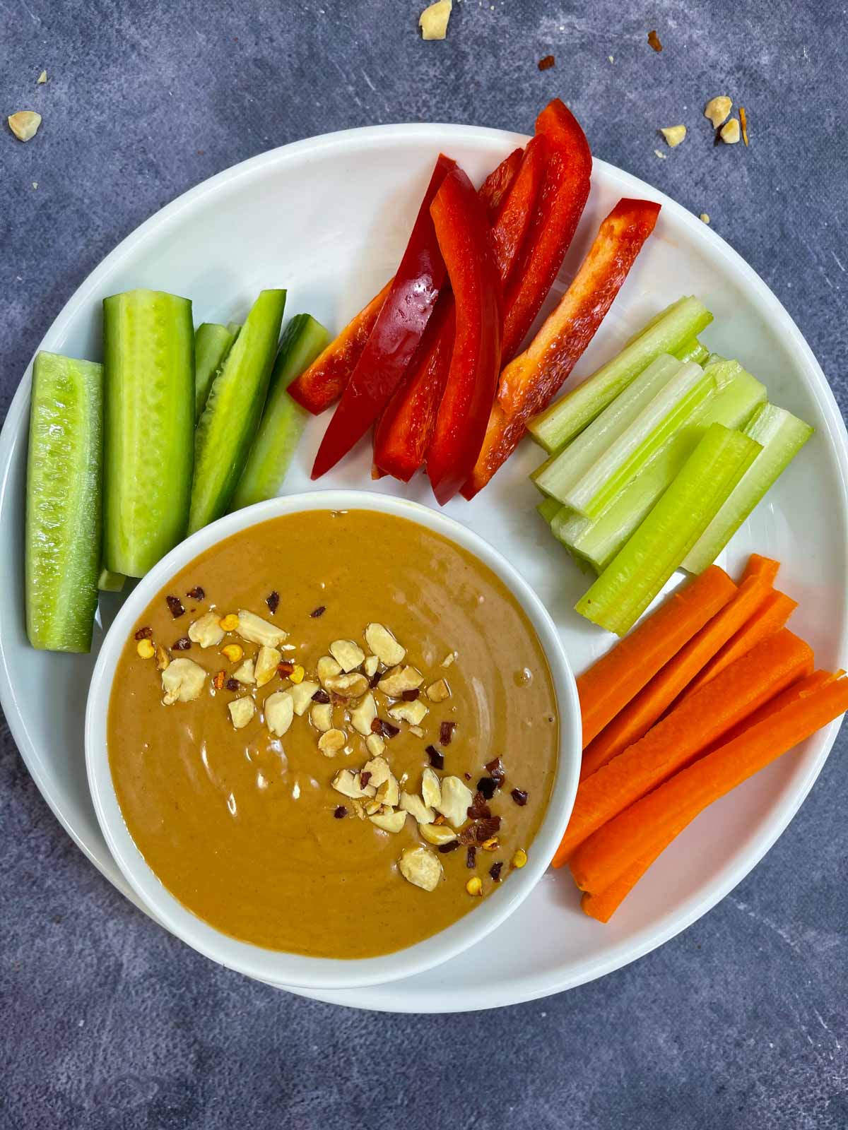 thai peanut dressing served in a bowl with raw veggies on the side