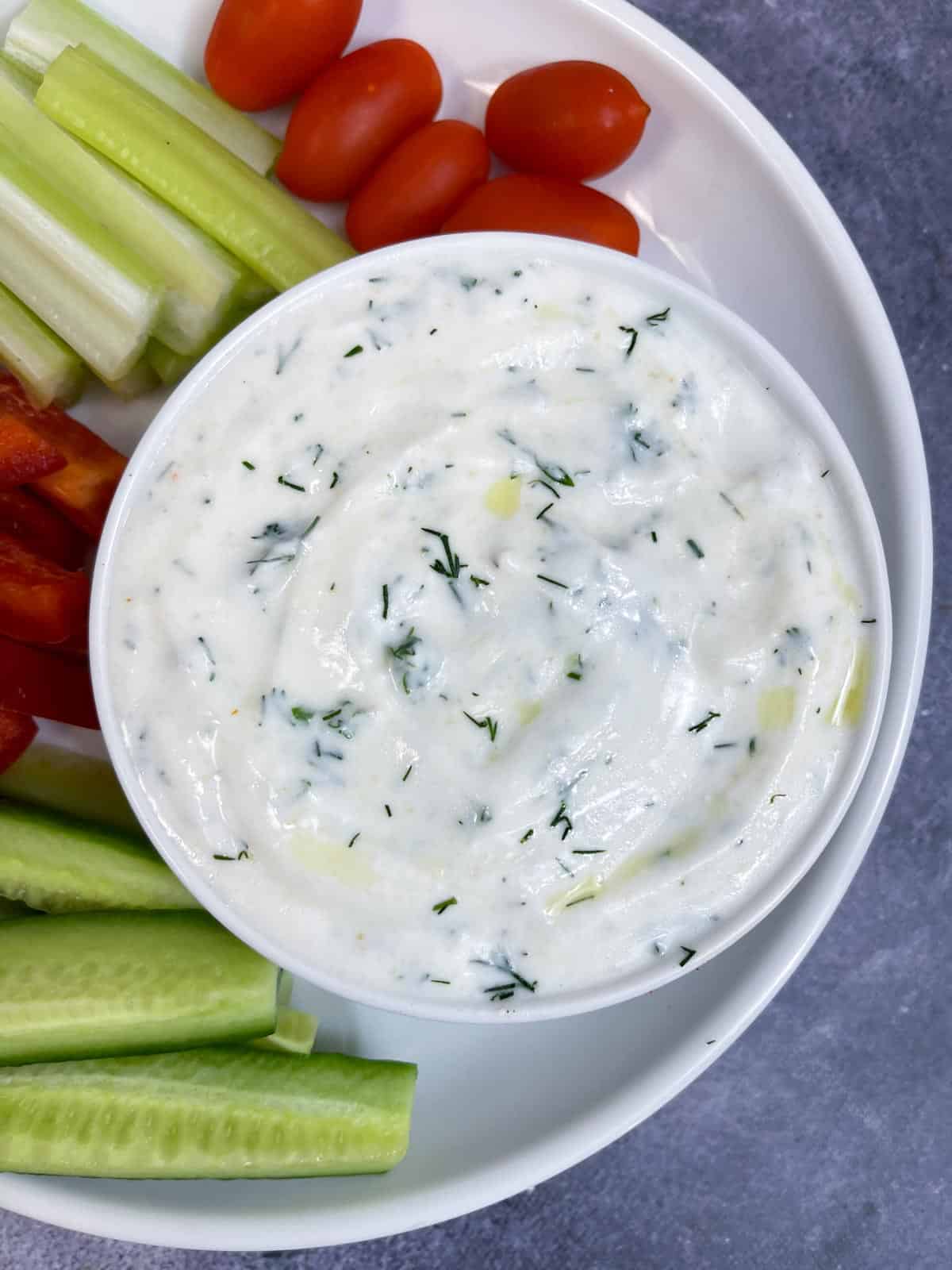 yogurt dill dip served in a bowl with side of veggies