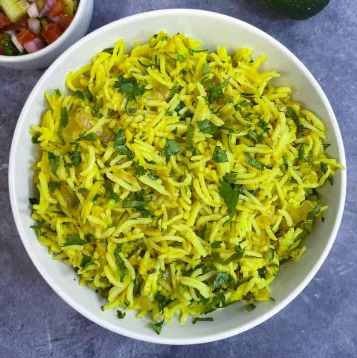 zucchini rice pilaf served in a bowl garnished with coriander leaves with side of salad