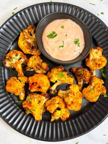 air fried cauliflower in a plate with sauce on the side