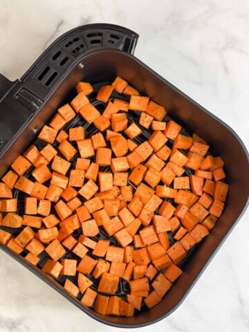 seasoned sweet potato cubes in the air fryer basket