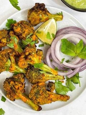 tandoori broccoli tikka served on a plate with lime wedge, onions and mint chutney collage
