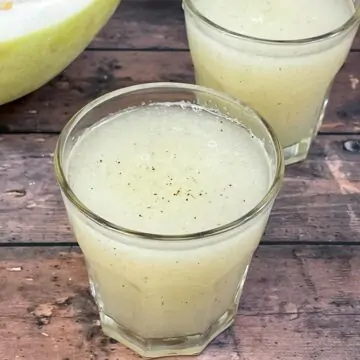 ash gourd juice (winter melon juice) served in a juice glass with a piece of ash gourd on the side