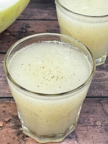 ash gourd juice (winter melon juice) served in a juice glass with a piece of ash gourd on the side