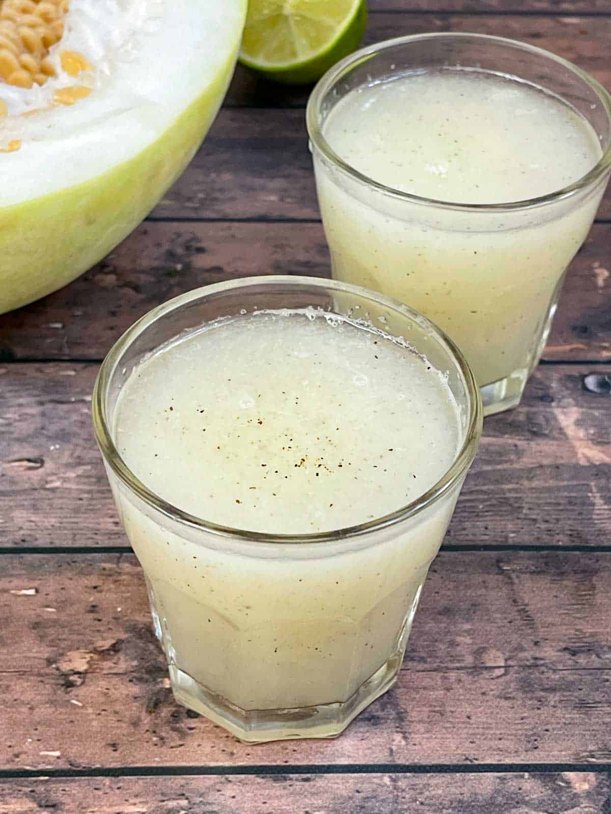 ash gourd juice (winter melon juice) served in a juice glass with a piece of ash gourd on the side