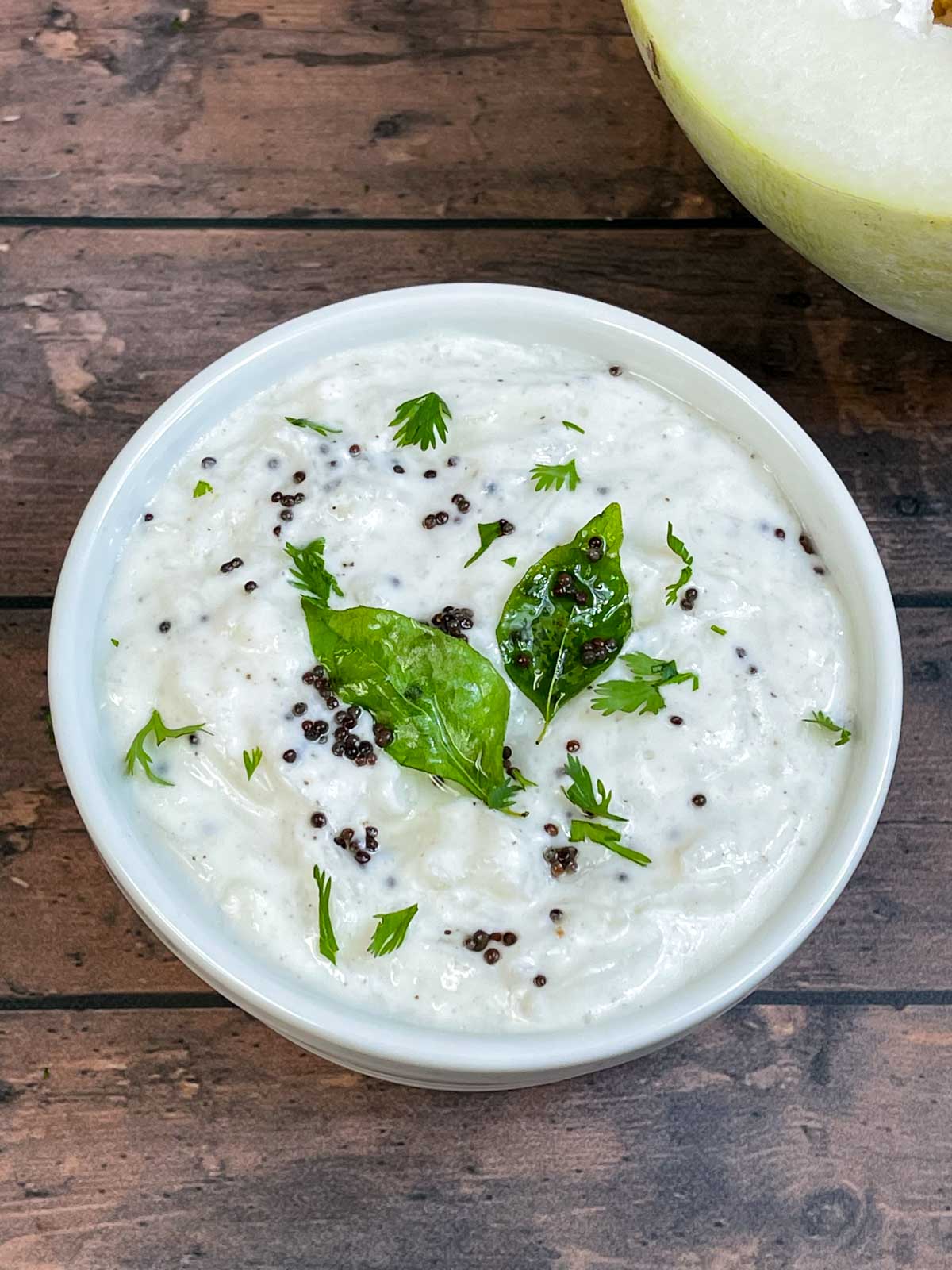 ash gourd raita served in a bowl garnished with cilantro