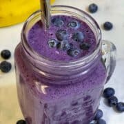 blueberry banana smoothie served in a mason jar with a steel straw