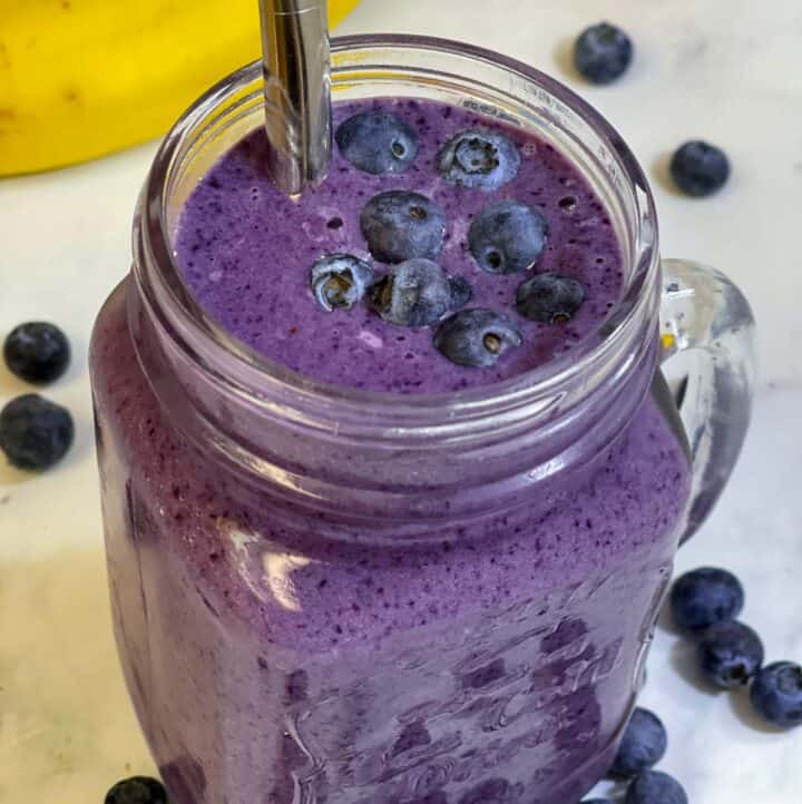 blueberry banana smoothie served in a mason jar with a steel straw