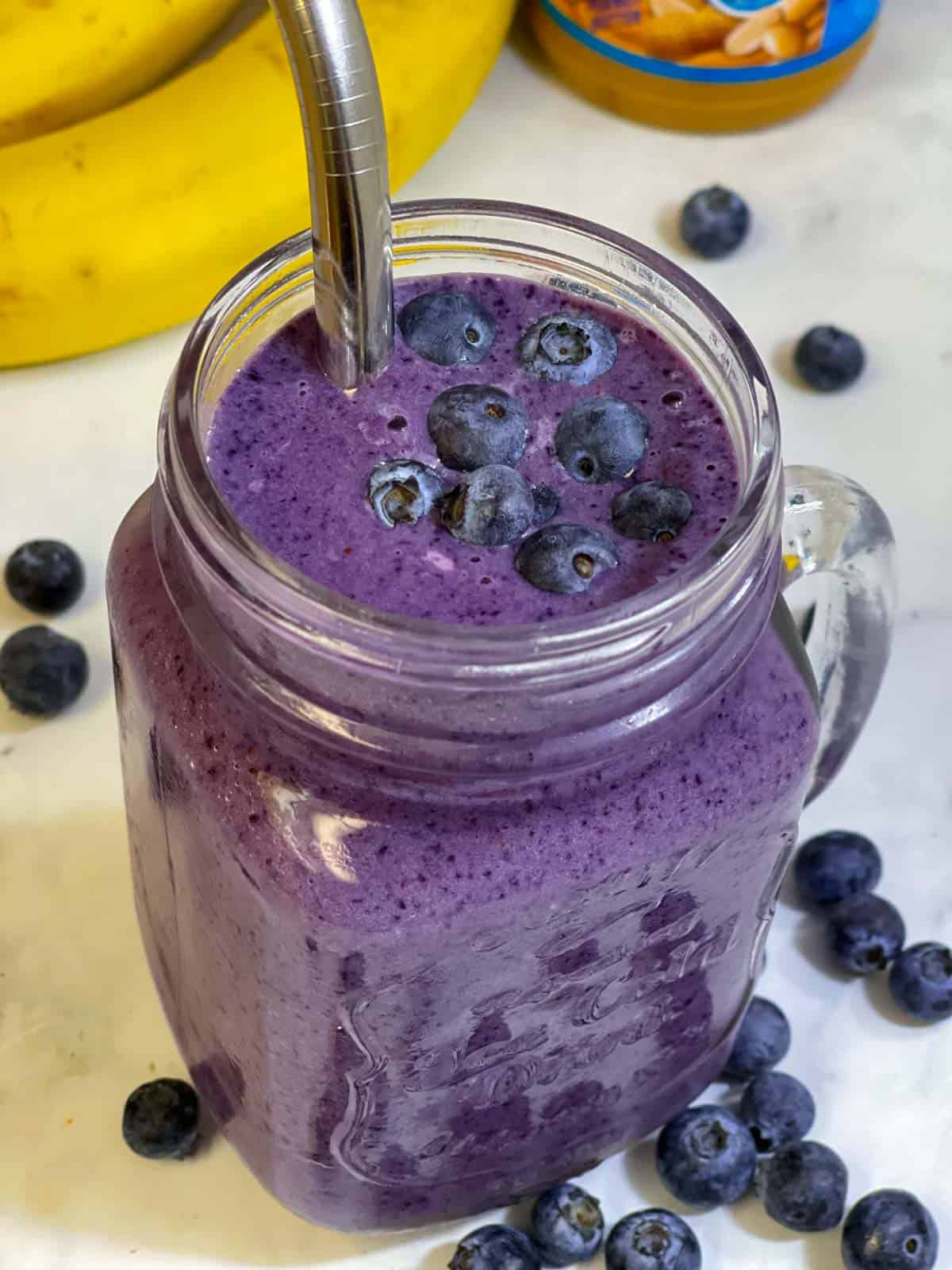 blueberry banana smoothie served in a mason jar with a steel straw 