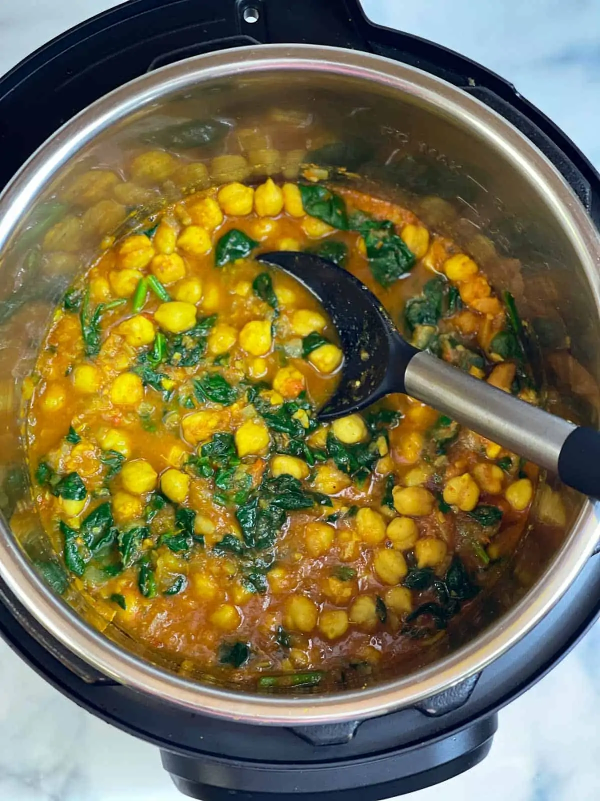 Chana saag recipe in an instant pot insert with a spoon