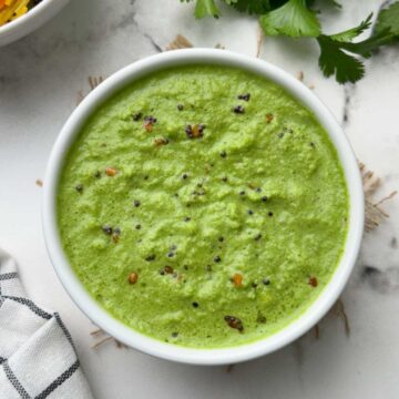 coriander coconut chutney served in a bowl with vermicelli upma and coriander leaves on the side