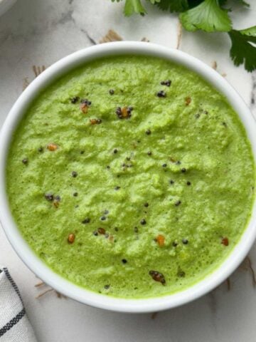 coriander coconut chutney served in a bowl with vermicelli upma and coriander leaves on the side