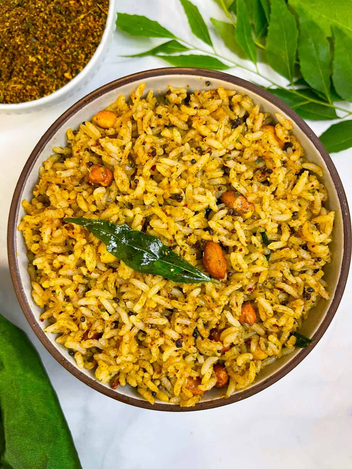 curry leaves rice served on a plate with podi and curry leaves in the side