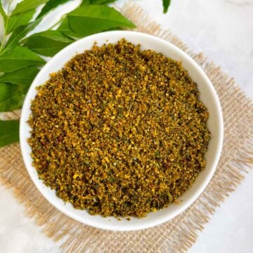 curry leaves chutney powder served in a bowl with side of curry leaves stalk