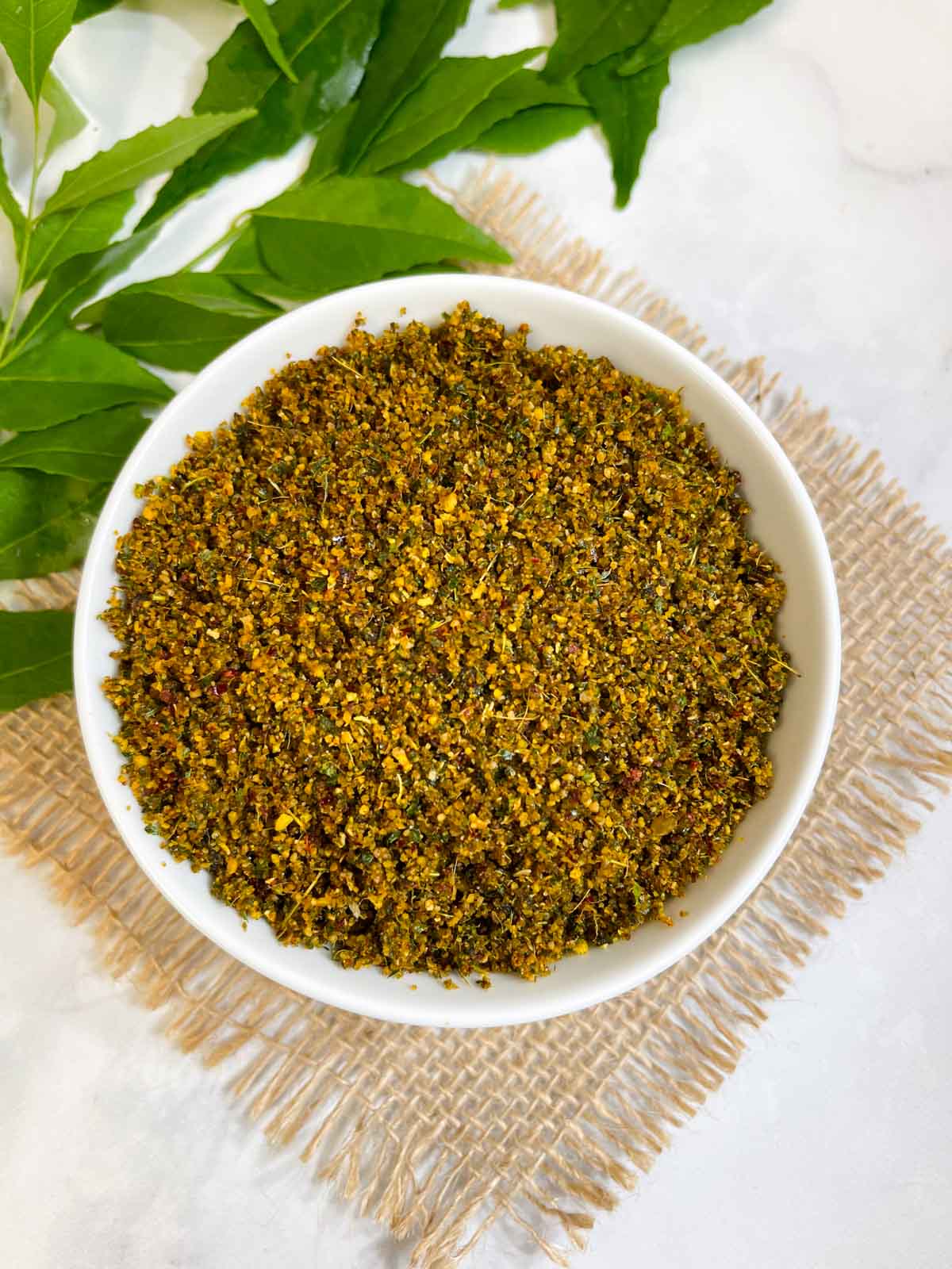 curry leaves chutney powder served in a bowl with side of curry leaves stalk