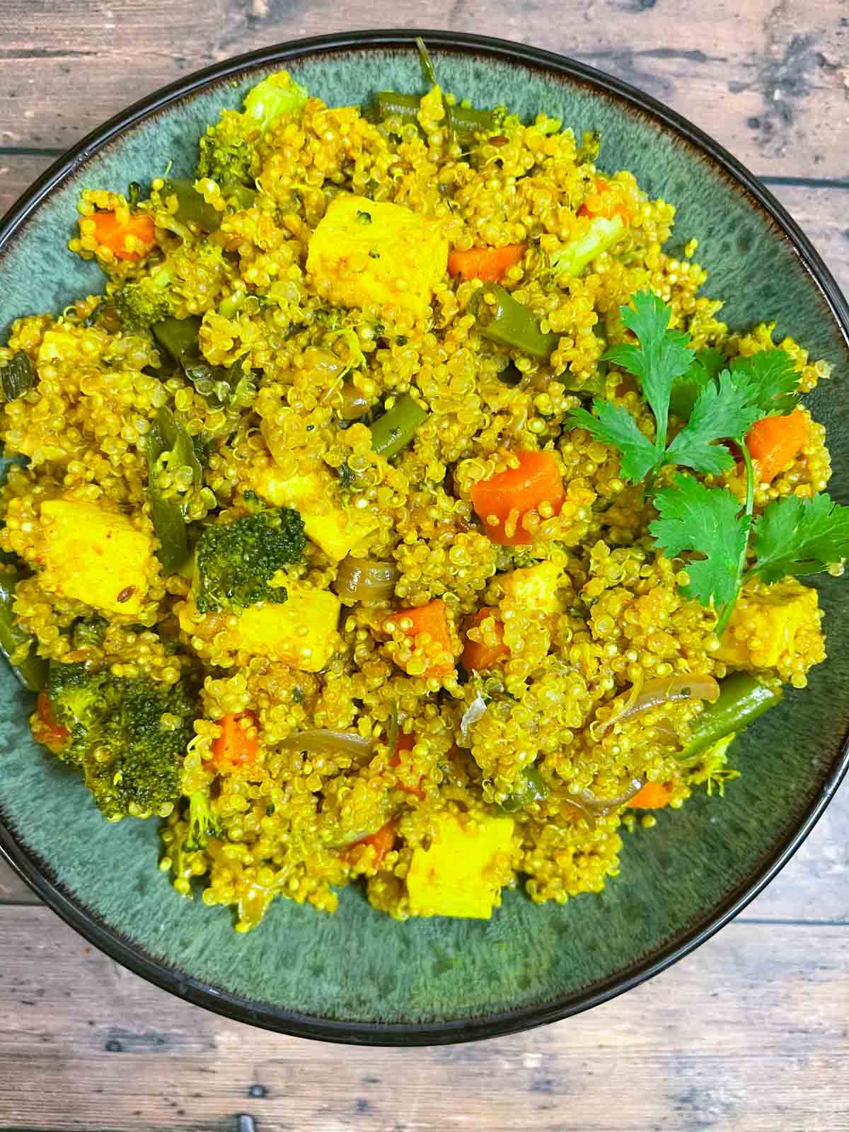 quinoa rice served in a bowl garnished with cilantro and served with side of raita