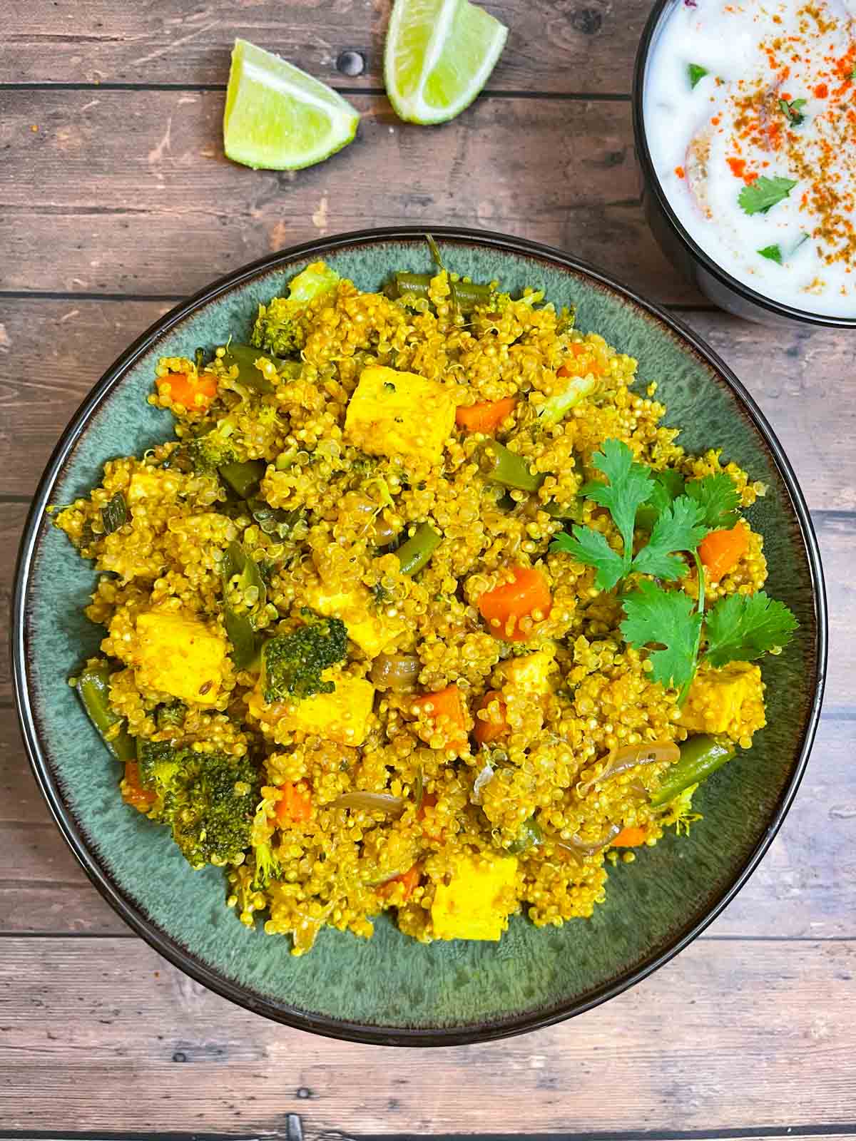 vegetable quinoa biryani served in a bowl garnished with cilantro and served with side of raita