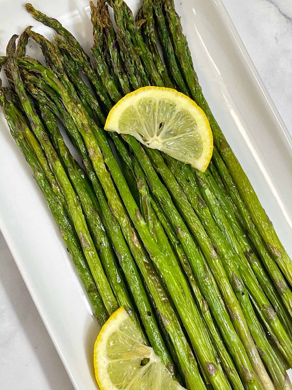 roasted air fryer asparagus served on a plate with two lemon wedges
