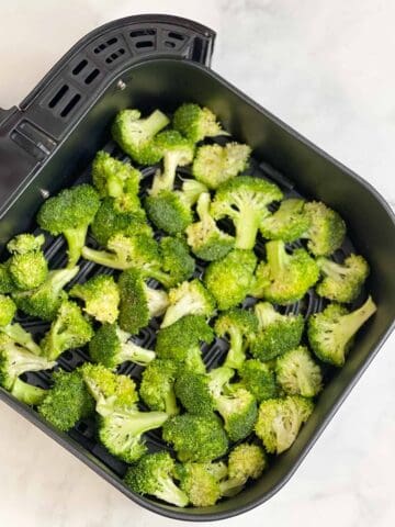 seasoned broccoli in the air fryer basket