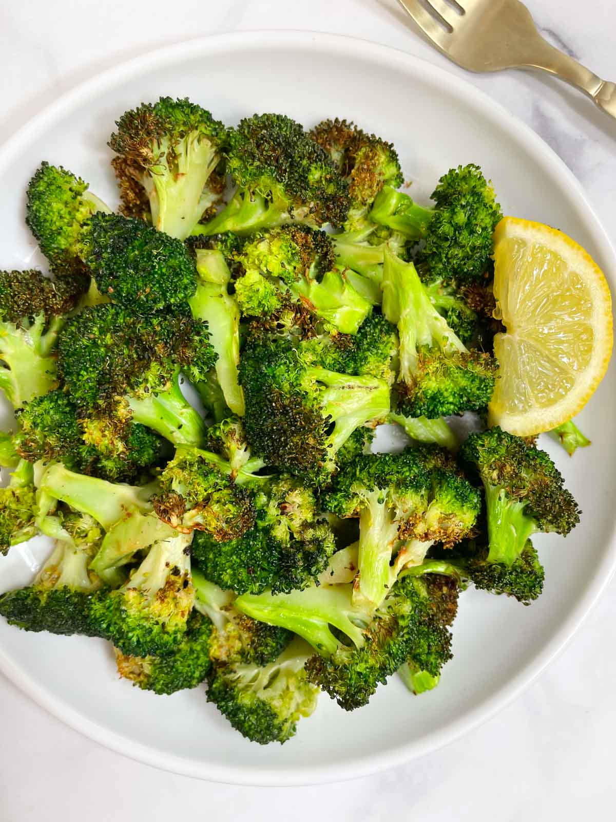 air fryer roasted broccoli served on a plate with lemon wedge on the side