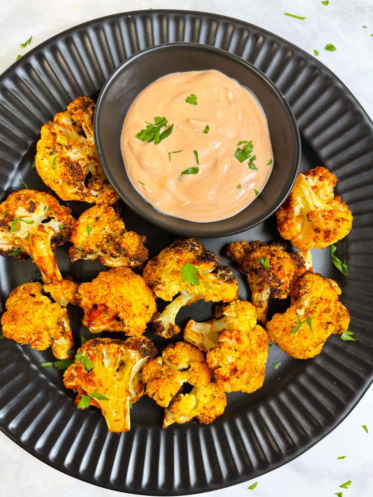 air fried cauliflower in a plate with sauce on the side