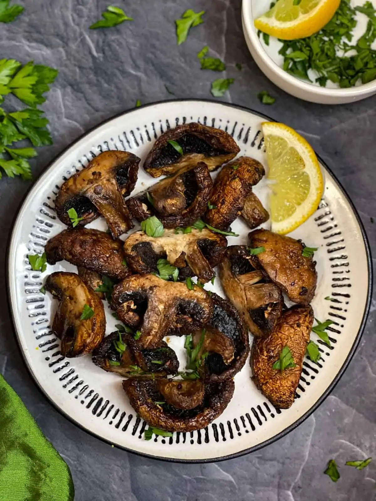air fryer mushroom on a plate garnished with cilantro with lemon wedge on the side