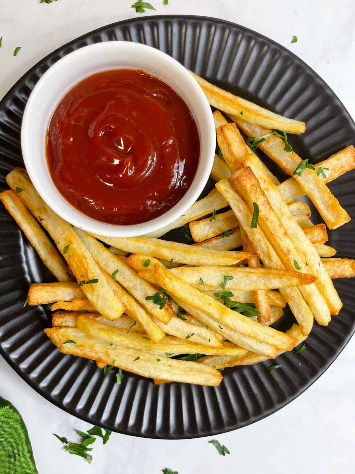 potato french fries made in air frier served on a plate with tomato ketchup