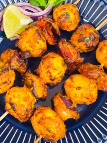 tandoori aloo served on a plate with lemon wedges and onion