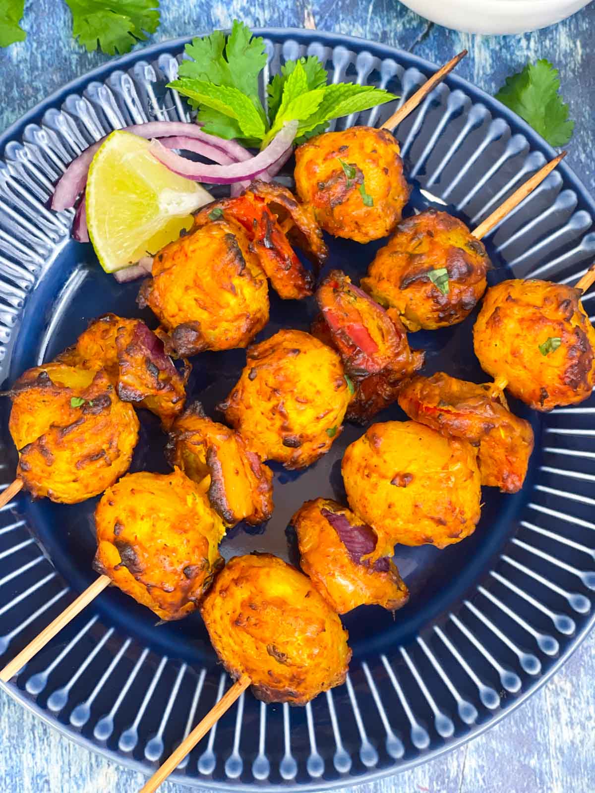 tandoori aloo served on a plate with lemon wedges and onion