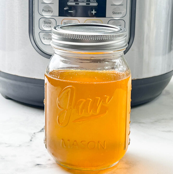homemade ghee stored in a glass jar in front of instant pot