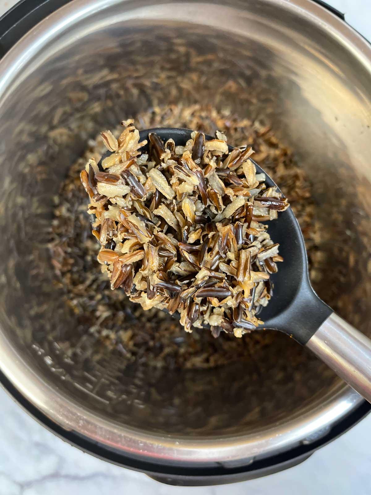 cooked wild rice in a ladle