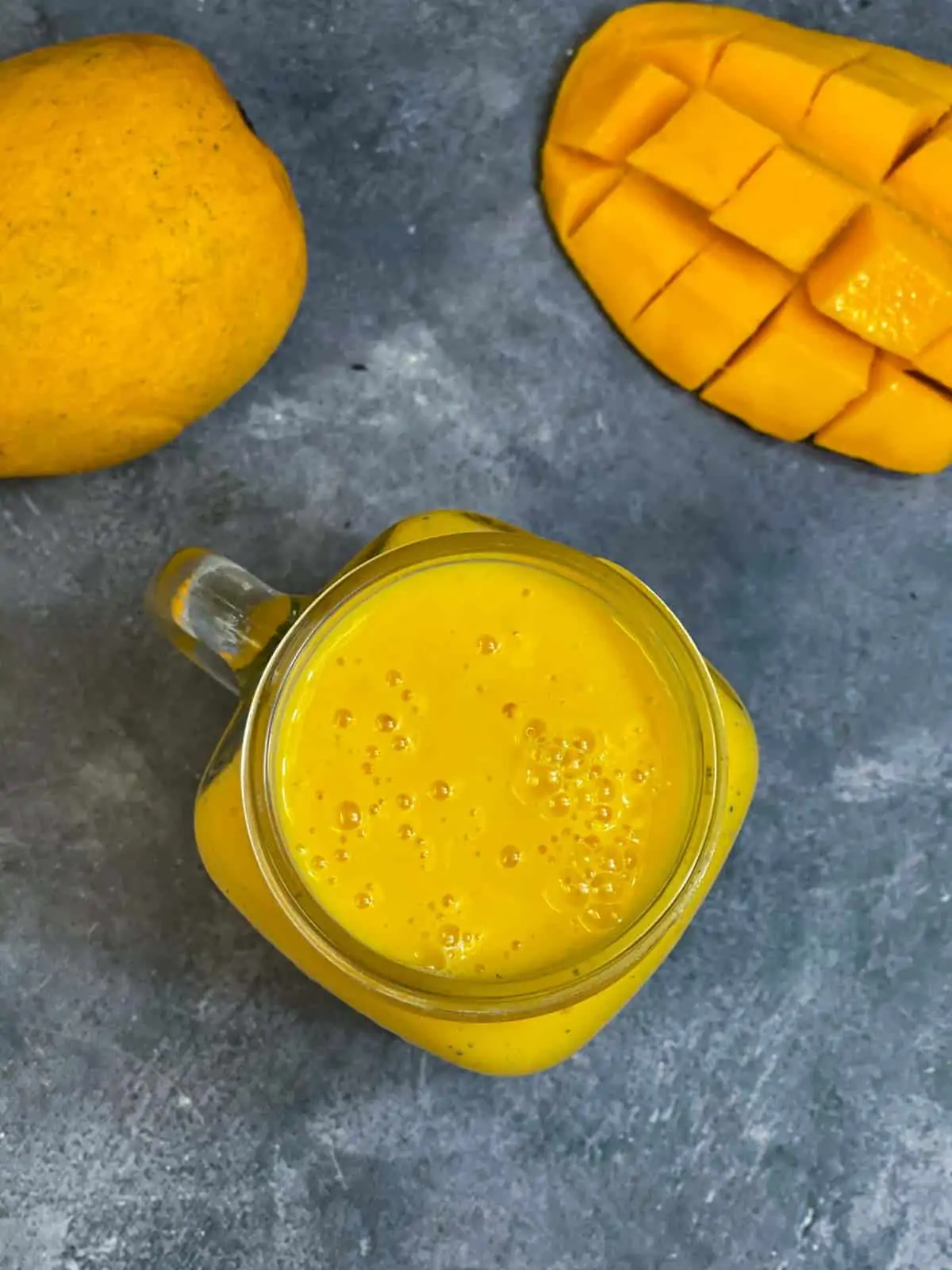 fresh mango milkshake served in a mason jar and mangoes on the side