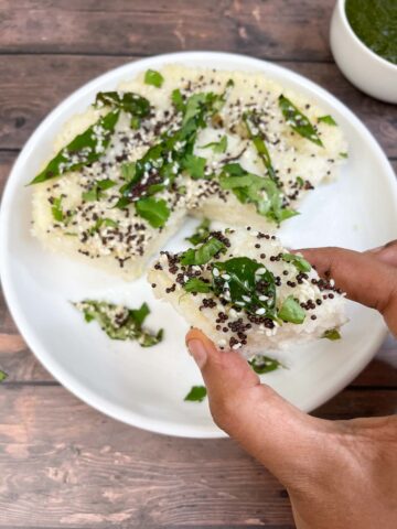 a diamond shaped sooji dhokla in hand