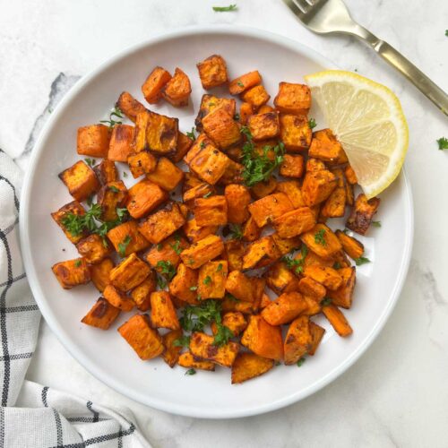 air fryer roasted sweet potatoes served on a plate with lemon wedge on the top