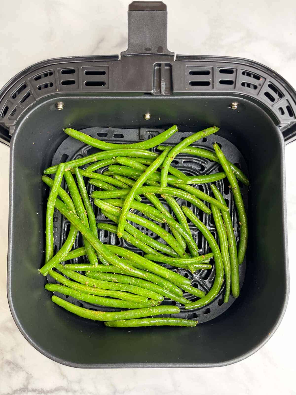 seasoned green beans in the air fryer basket