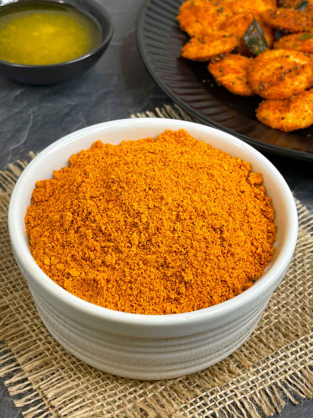 idli podi served in a bowl with ghee and podi idli on the side