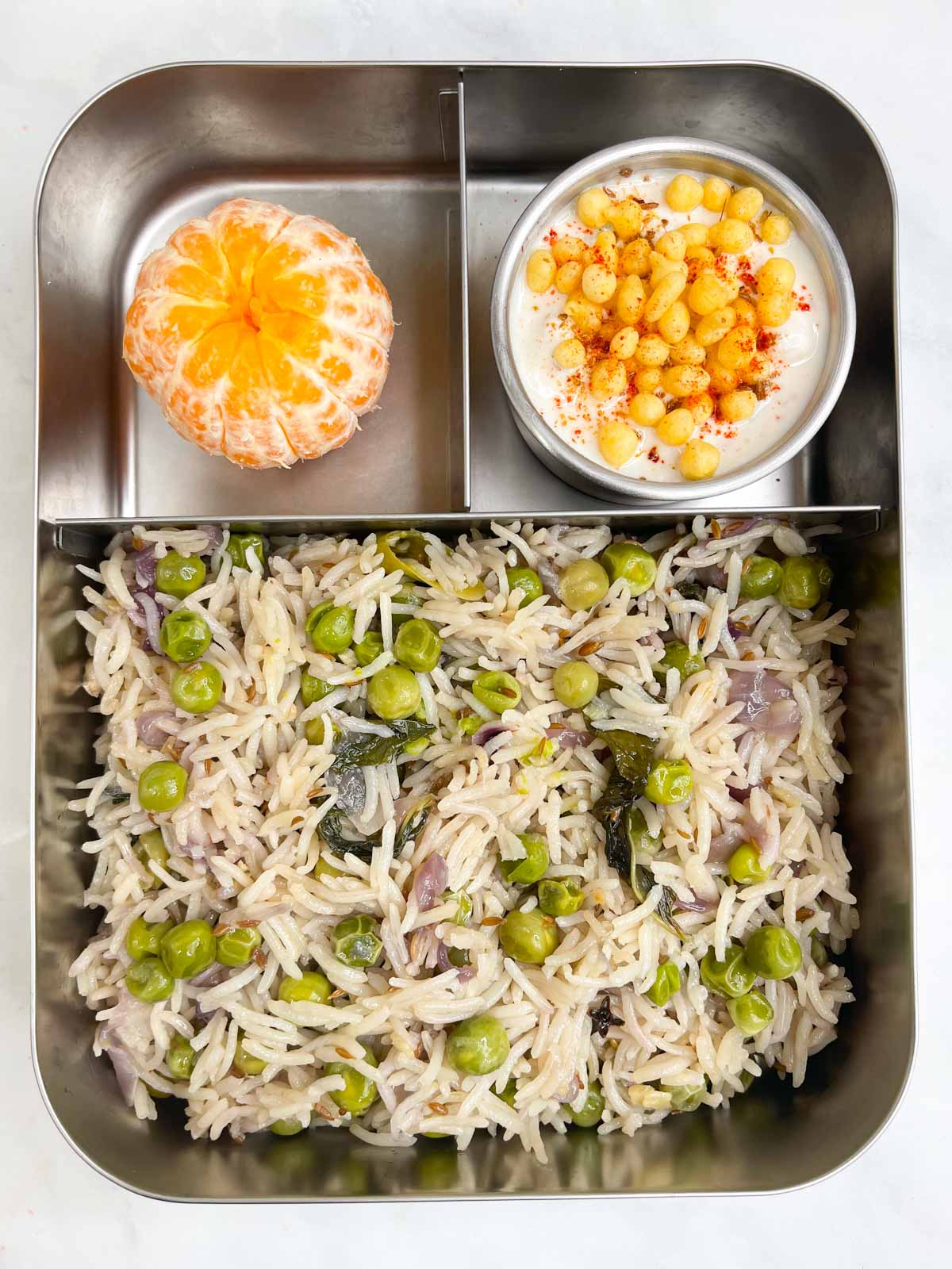 green peas pulao with boondi raita and orange in steel lunchbox