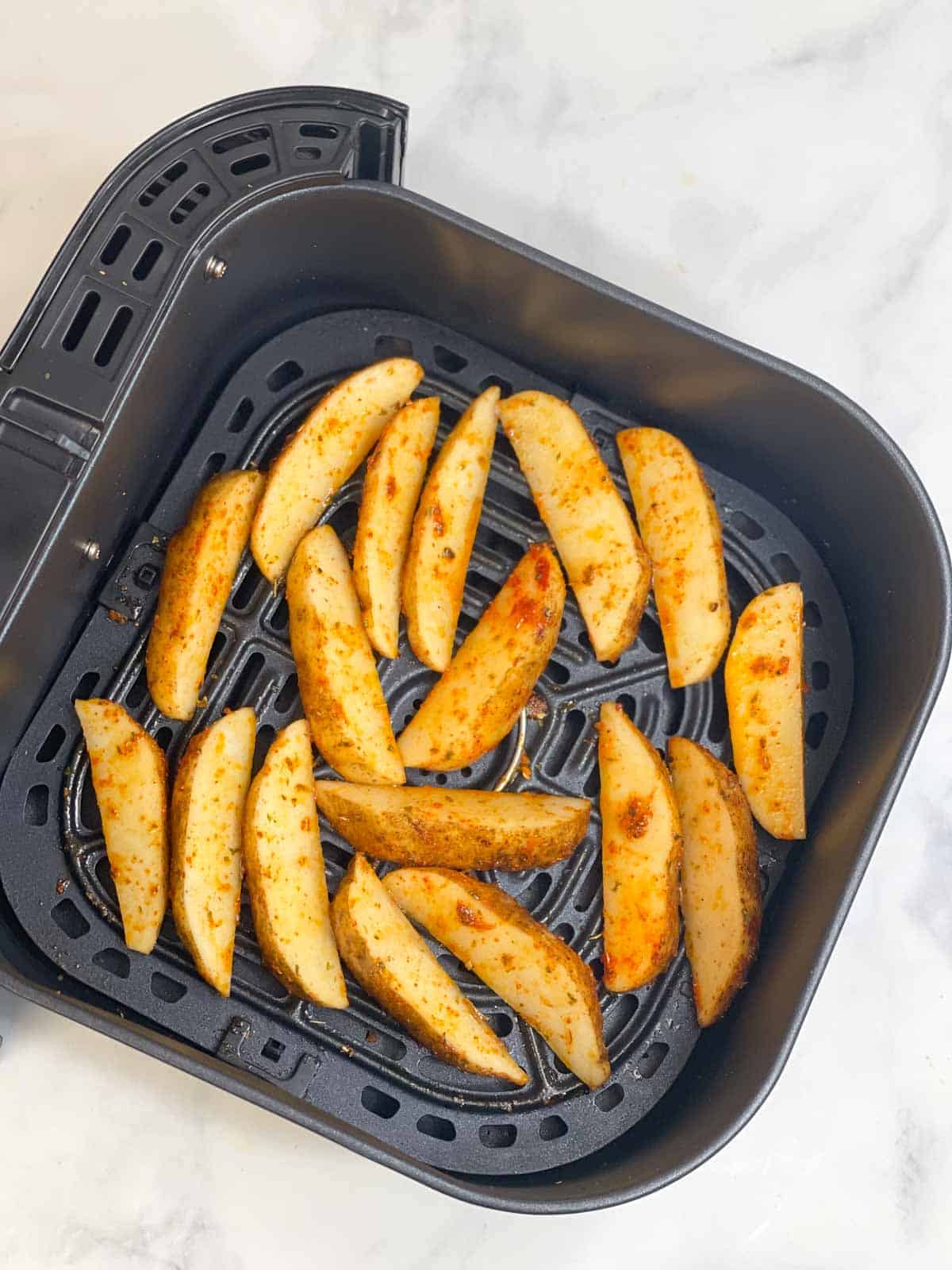 seasoned potato wedges in the air fryer basket 