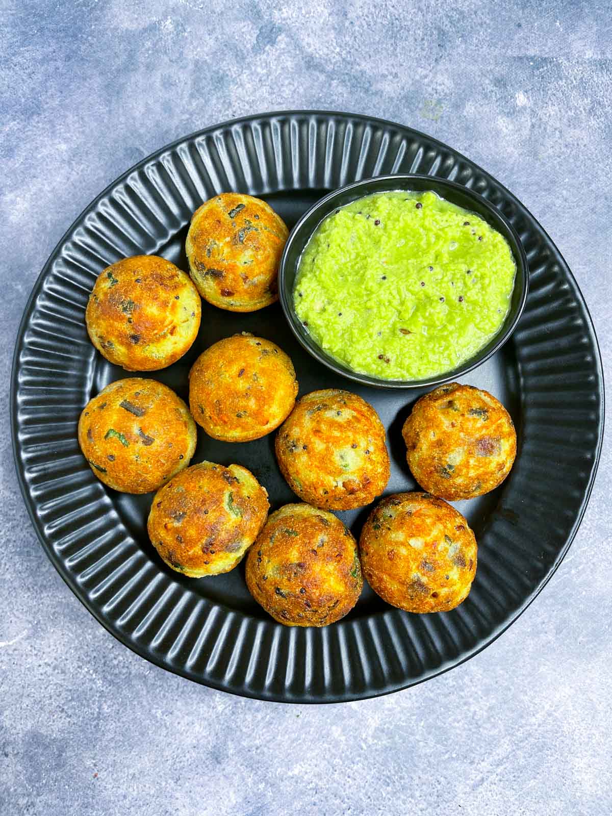 rava paddu served on a plate with coconut chutney on the side