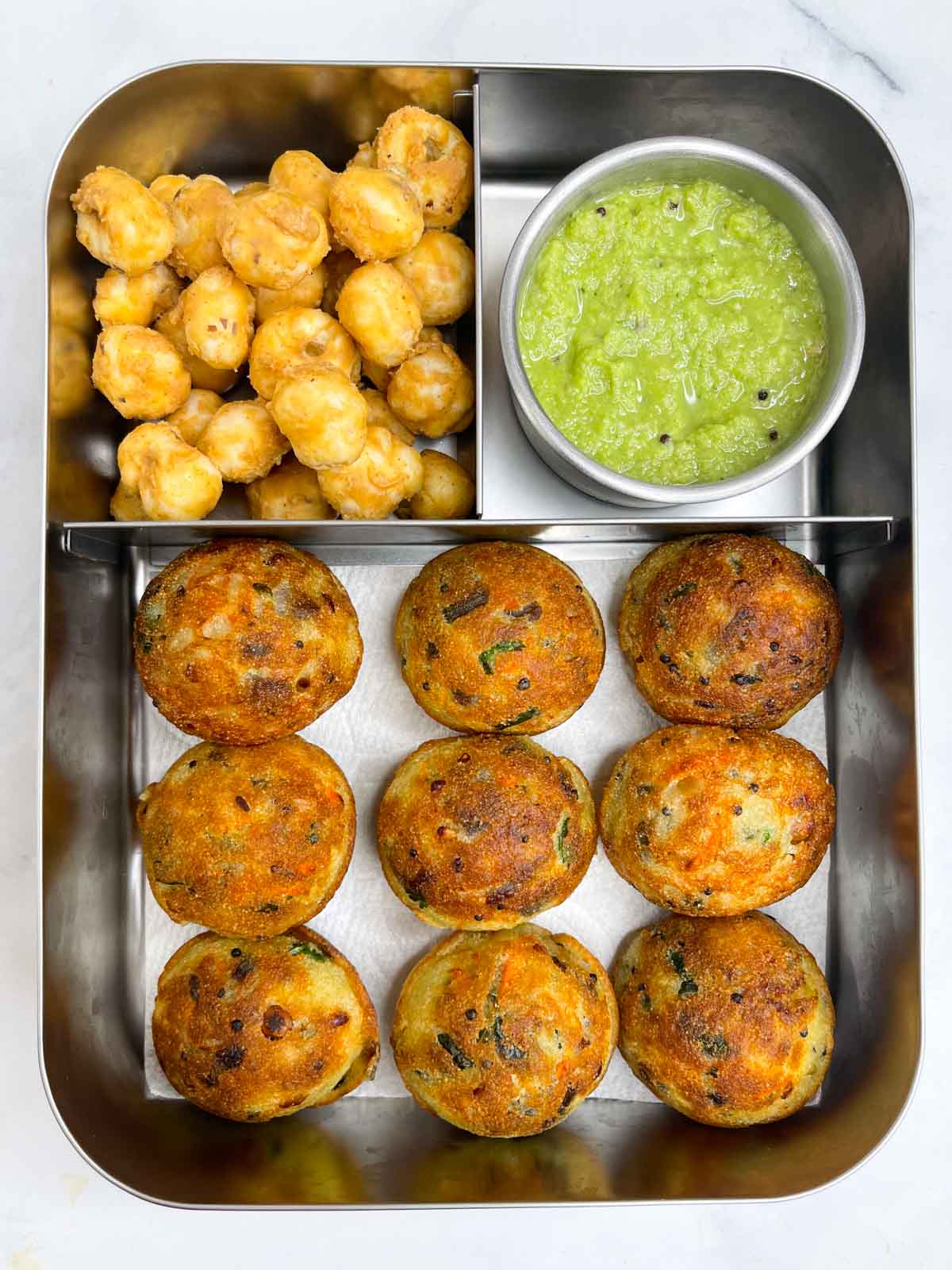 Rava paddu, coconut chutney and peanut butter makhana in bento steel lunch box.